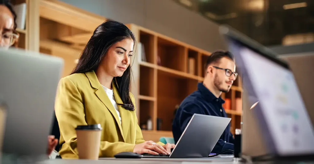 Legal professionals working on laptops in a modern office setting, focused on digital collaboration and technology-driven workflows.