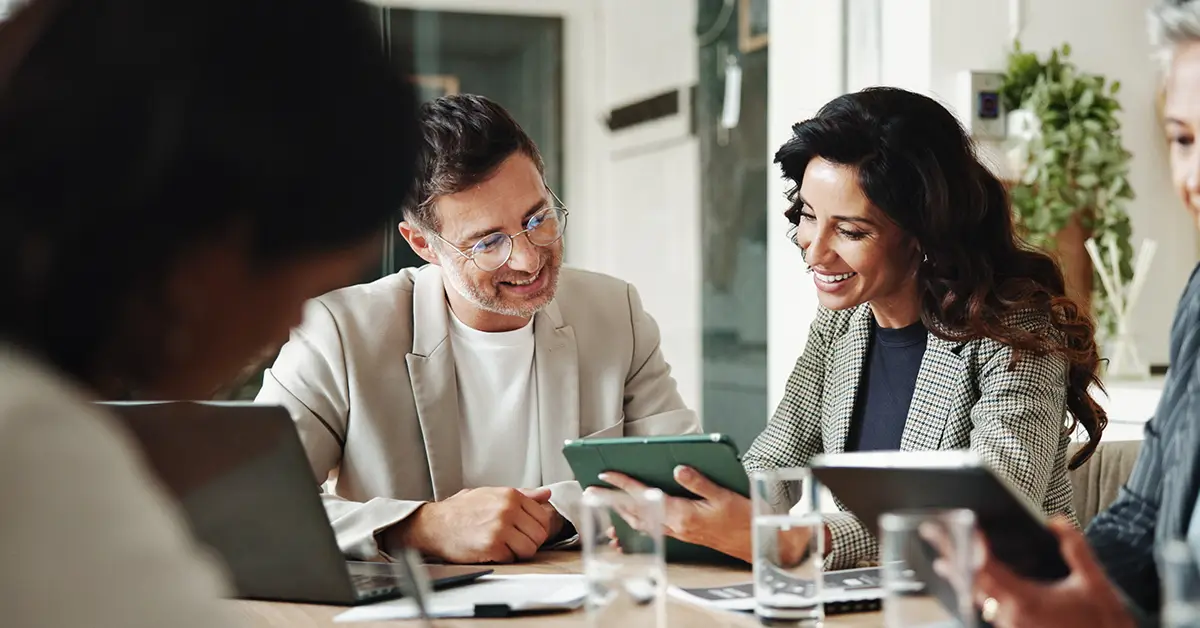 Diverse group of professionals in a modern office, collaborating around a table with digital devices, representing seamless Salesforce contract management integration.