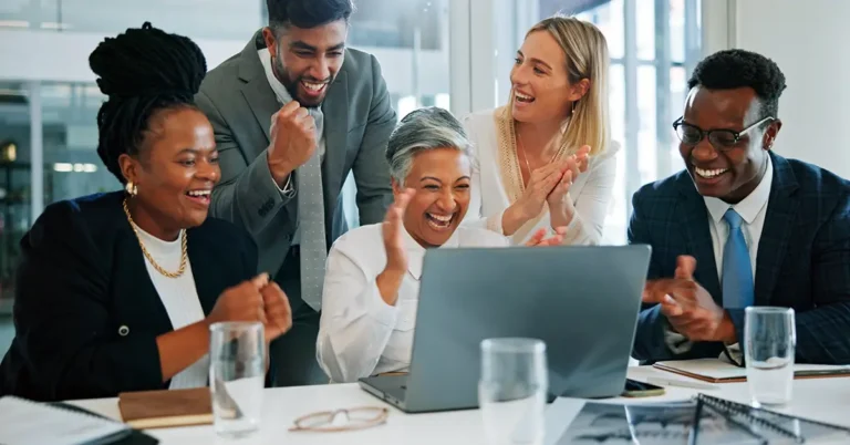 Business team celebrating success at a laptop in a bright office, representing ContractPodAi named IDC MarketScape Leader in 2025.
