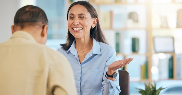 businesswoman in blue shirt sits across from a colleague in a modern office, symbolizing ContractPodAi global team expansion and collaboration.
