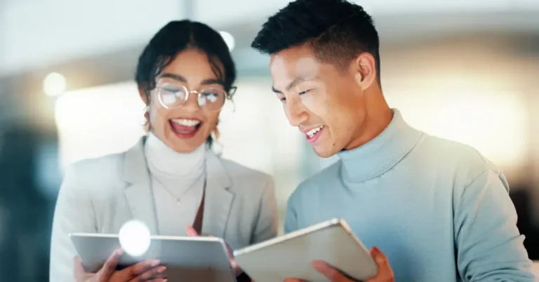 Two legal professionals smiling and collaborating on tablets in a modern office, symbolizing AI-powered contract management and GPT-5 driven legal intelligence from ContractPodAi.
