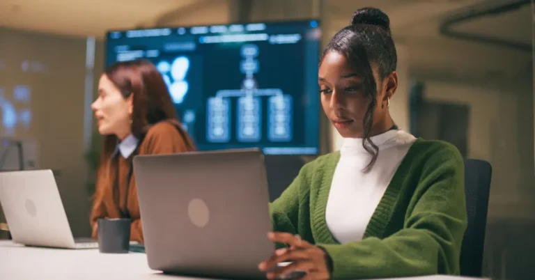 Two professionals working on laptops in a modern office, symbolizing enterprise contract management's role in digital legal operations for 2025.