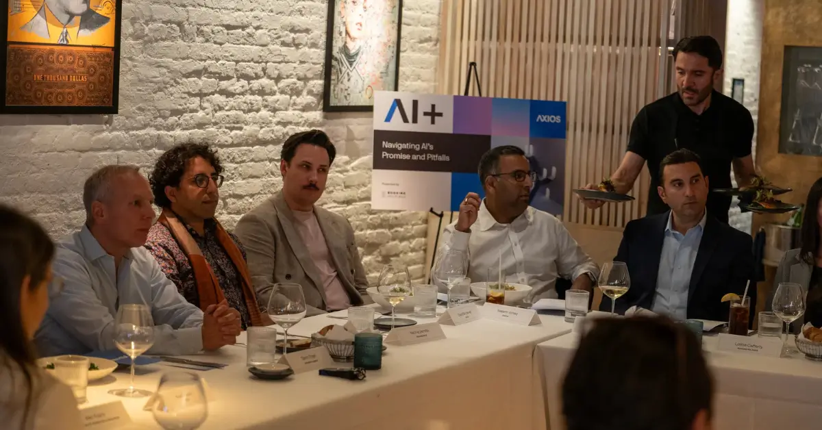 Business leaders seated at a dinner table during an Axios AI+ event titled “Navigating AI’s Promise and Pitfalls,” with food being served.