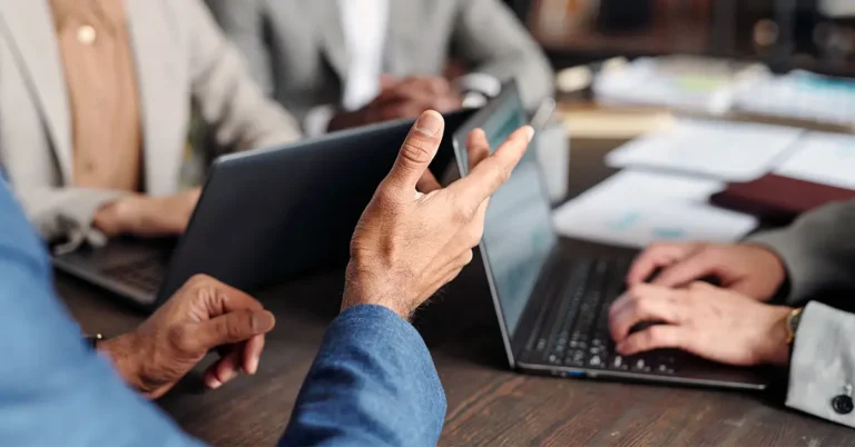 Business professionals in a collaborative meeting discussing CLM RFP strategy with laptops and documents on the table.